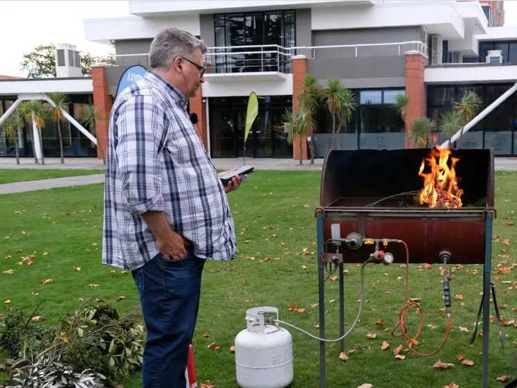 Dr Tim Curran watches plant material burn on a bbq